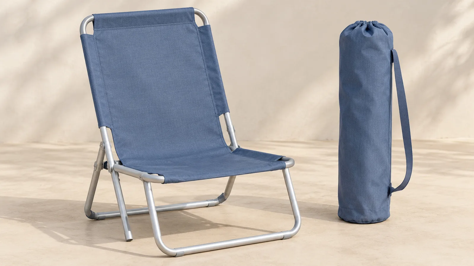 Isang plain na natitiklop na upuan sa tabing-dagat na ipinakitang bukas sa tabi nito na katugmang naka-pack na carry bag